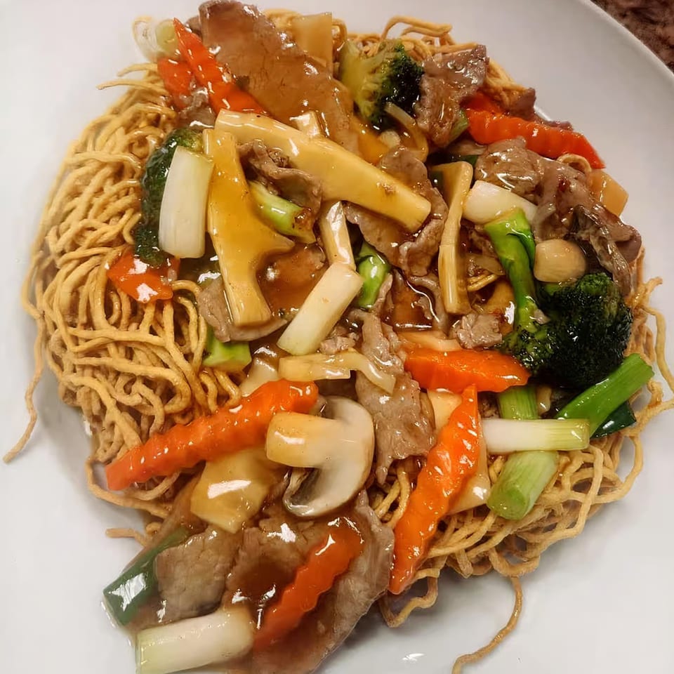 Crispy egg noodles topped with beef, broccoli, carrots, mushrooms, and bamboo shoots in a savory sauce.